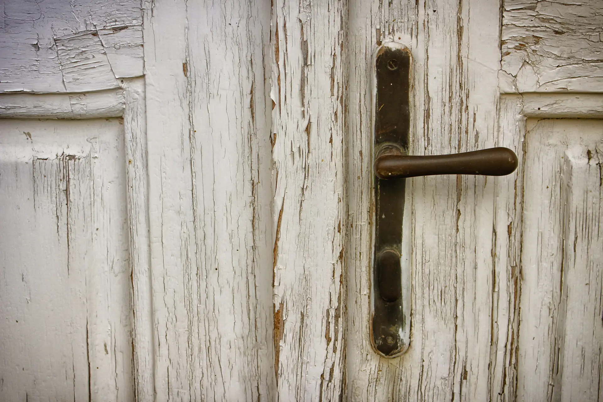 La vieille porte peinte en blanc de l’arrière-boutique, sa poignée de fer